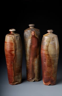 three vases are sitting in the dark with one woman standing behind them and another person looking at it