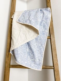 a blue and white blanket sitting on top of a wooden ladder