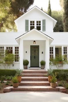 a white house with potted plants and steps leading up to the front door area