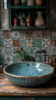 a bowl shaped sink sitting on top of a wooden counter next to a green cabinet