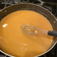 a pan filled with liquid and whisk on top of an oven burner