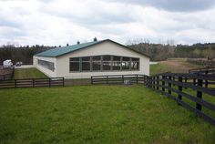 a white building sitting on top of a lush green field next to a black fence