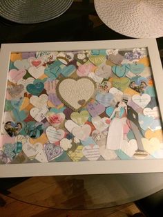 a white frame filled with lots of heart shaped magnets on top of a table