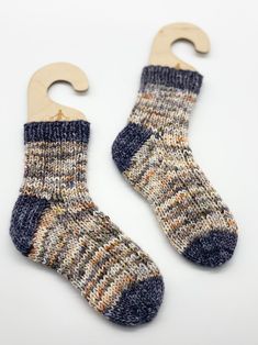 two pairs of socks hang from hooks on a white background, one is blue and the other is brown