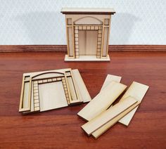 three pieces of wood sitting on top of a wooden table next to a small doll house