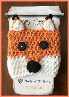 an orange and white crocheted fox head on top of a cardboard box with the words cup co