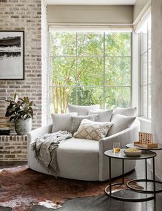 a living room filled with furniture next to a brick wall and window covered in windows