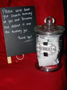 a glass jar sitting on top of a red couch next to a sign that says please write down your favorite memory or you and bran