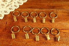 six pairs of brass - plated keychains on a wooden table with doily