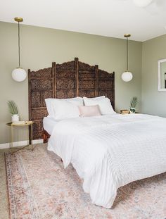 a bedroom with a bed, rug and two lamps hanging from the ceiling above it