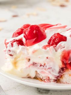 a close up of a piece of cake on a plate with whipped cream and cherries