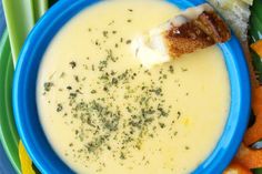 a blue plate topped with a bowl of soup next to bread and veggies