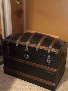 an old trunk sitting on the floor in front of a door with roped handles