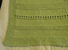 a green crocheted blanket sitting on top of a bed