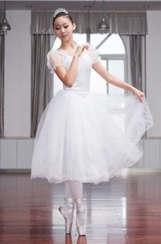 a woman in a white dress is standing on a wooden floor