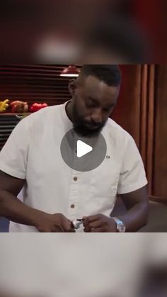 a man standing in front of a table holding a cell phone and looking at it