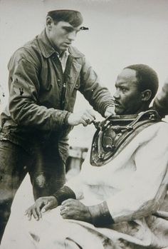 an old black and white photo of two men cutting another man's hair with scissors