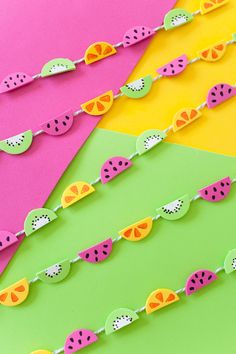 watermelon slices and oranges are on a colorful paper chain that is attached to a pink, green, yellow, and red card board