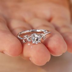 a close up of a person's hand holding a ring with a diamond on it