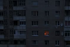 an apartment building lit up at night with the lights on and windows open in front of it