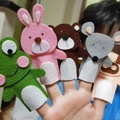 a person holding up several hand puppets made to look like animals and bears in different colors