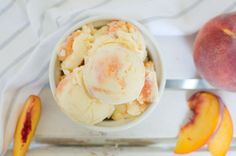 a bowl filled with ice cream next to two peaches