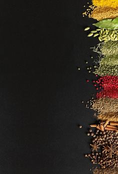 an assortment of spices and herbs arranged on a black background with space for text or image