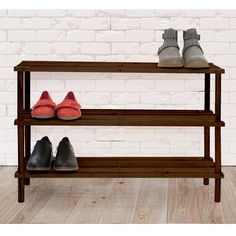 two pairs of shoes are sitting on a wooden shoe rack in front of a brick wall