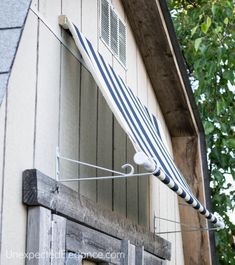 an awning hanging from the side of a building next to a window with shutters