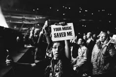 a man holding up a sign that says your music saved me in front of an audience