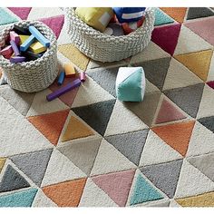 two baskets filled with toys sitting on top of a colorful floor covered in carpeting