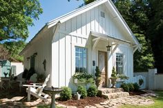 a small white house sitting on top of a lush green field