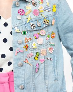 a woman wearing a denim jacket with lots of pins on it