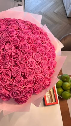 a large bouquet of pink roses sitting on top of a table next to some green olives