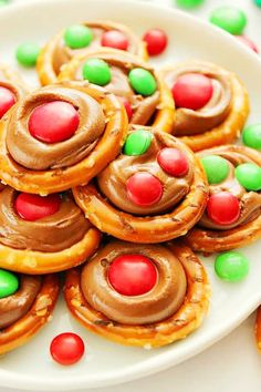 a white plate topped with mini pretzels covered in chocolate frosting and candy