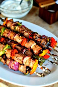 several skewers of meat and vegetables on a white plate