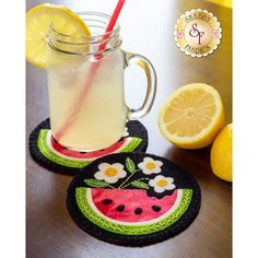 two coasters that have watermelon slices and lemonade in them on a table