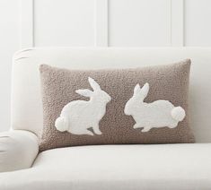 a white couch with two pillows that have rabbits on them