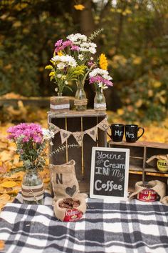 a table topped with vases filled with flowers on top of a checkered blanket