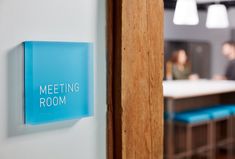 a blue sign that says meeting room hanging on the side of a wall in an office