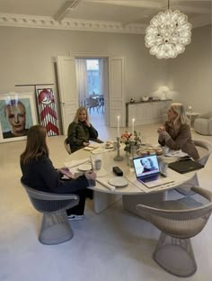 three women sitting around a table with laptops