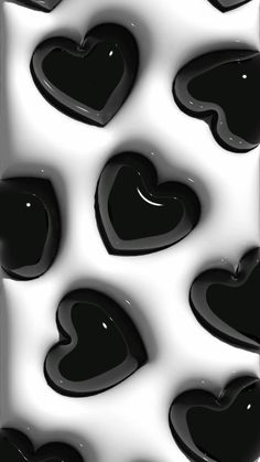 some black hearts are in the air on a white and black background with water droplets