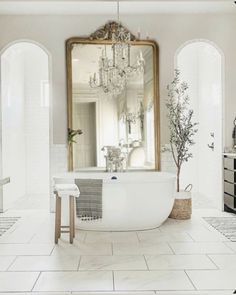 a bathroom with a tub, mirror and chandelier