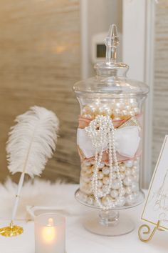 a white table topped with a glass jar filled with lots of pearls and other items