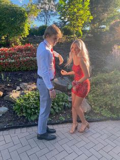 a man in a suit and tie standing next to a woman wearing a red dress