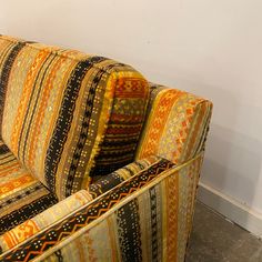 an orange and black striped couch sitting on top of a floor next to a white wall