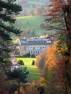 an old building in the middle of trees with fall foliage on it's sides