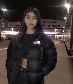 a woman standing in the middle of an empty parking lot at night with her hands on her hips