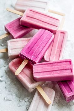 several popsicles with pink and white toppings on top of ice flaked