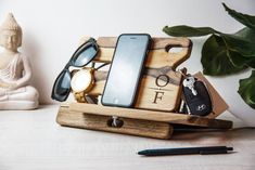 a cell phone sitting on top of a wooden stand next to a pen and glasses